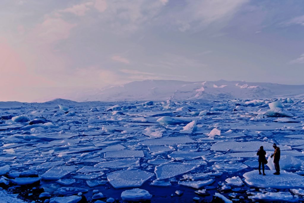 Two people standing on an ice floe among hundreds of other ice floes