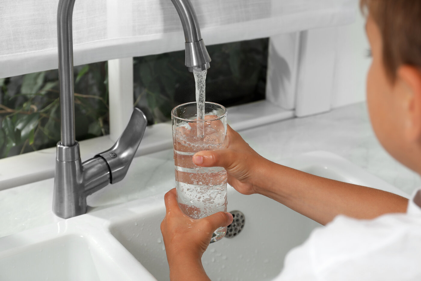 Boy filling a glass with water from faucet