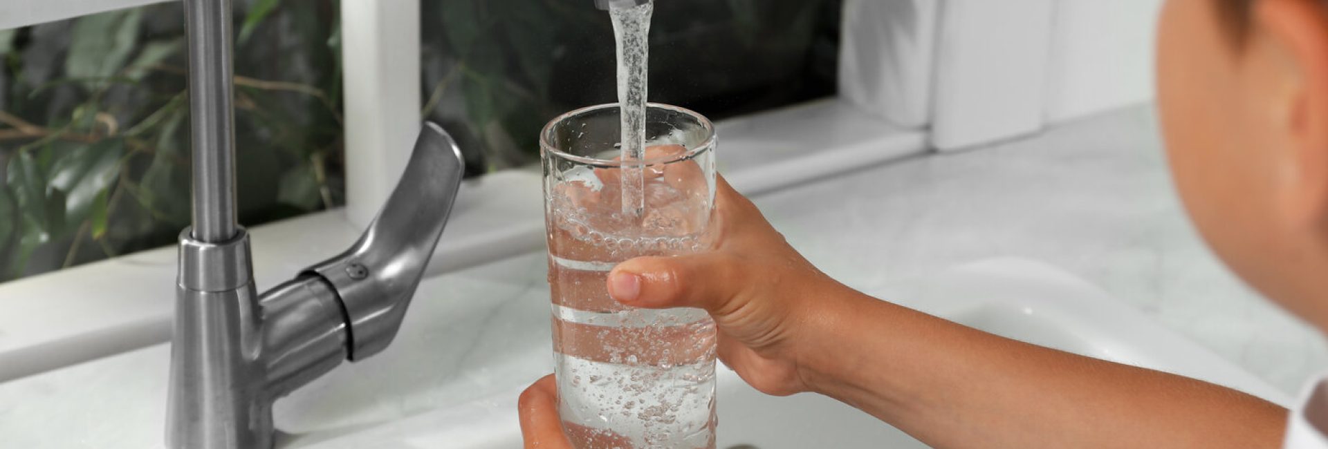 Boy filling a glass with water from faucet